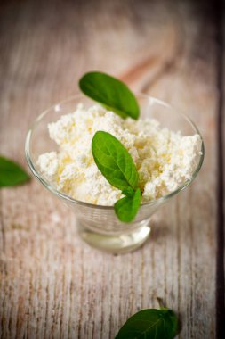 Taze organik süzme peynir ahşap bir masada cam bir kasede.