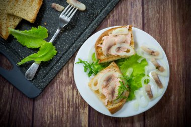 Salatalı sandviç, ringa balığı ve masada soğanlı otlar.