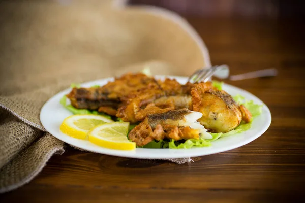 Жареная тушеная рыба в тесте с салатом и лимоном в тарелке — стоковое фото