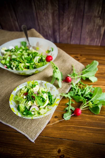 Vårsallad från tidiga grönsaker, salladsblad, rädisor och örter på bordet — Stockfoto