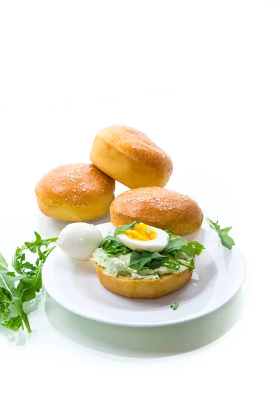 Homemade bun with cheese spread, fresh arugula and boiled egg in a plate — Stock Photo, Image