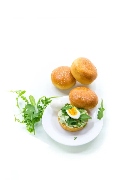 Hausgemachtes Brötchen mit Käseaufstrich, frischem Rucola und gekochtem Ei in einem Teller — Stockfoto