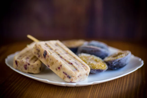 Helado casero dulce de ciruela en un palo con rebanadas de ciruela en el interior, en un plato —  Fotos de Stock