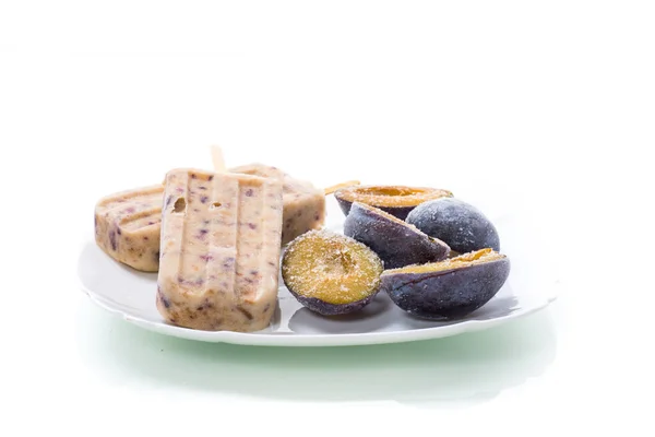 Helado casero dulce de ciruela en un palo con rebanadas de ciruela en el interior, en un plato — Foto de Stock