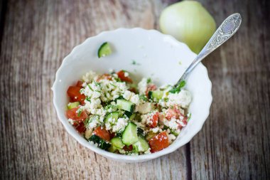 Salatalıklı taze süzme peynir salatası ve kabında otlar olan domates.
