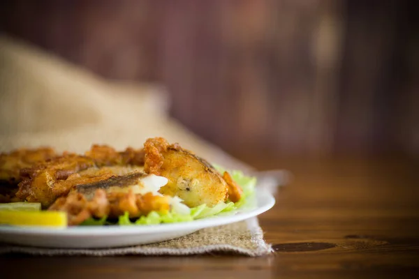 Жареная тушеная рыба в тесте с салатом и лимоном в тарелке — стоковое фото