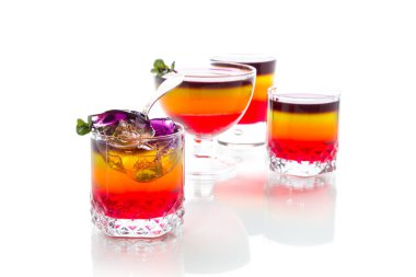 Beyaz arka planda izole edilmiş cam bir fincanda çok renkli meyveli puf jöle.