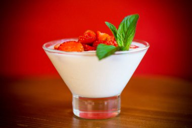 Tahta bir masada cam bir kasede kırmızı taze çilekli ev yapımı yoğurt.