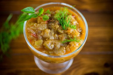 Ahşap bir masada, içinde baharatlar olan pişmiş patlıcan havyarı.