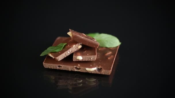 Γλυκιά μαύρη σοκολάτα με ξηρούς καρπούς σε μαύρο φόντο — Αρχείο Βίντεο