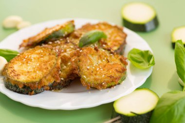 Susam tohumları ve taze fesleğenin altında kızarmış kabak parçaları..