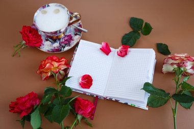 Güllerle dolu romantik bir sabah, bir defter ve bir fincan kapuçino..
