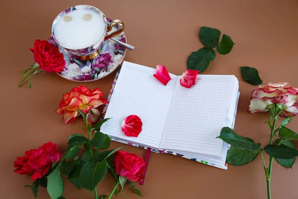 Güllerle dolu romantik bir sabah, bir defter ve bir fincan kapuçino..