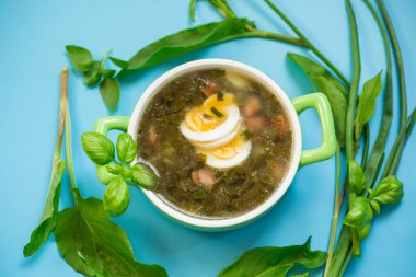 Mavi arka planda yumurta ve doru yeşil bir borş tabakasının üst görüntüsü..