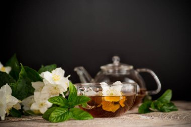 Yasemin çiçekleri ve çay siyah arka planda bir fincanda.