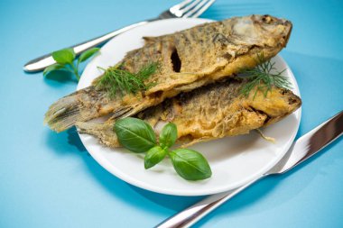 Beyaz tabakta çıtır çıtır altın kabuklu kızarmış sazan balığı..