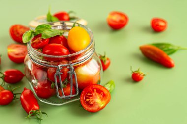 Yeşil arka planda fesleğenli çeşitli kiraz domatesleri..