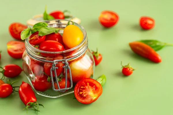 Yeşil arka planda fesleğenli çeşitli kiraz domatesleri..