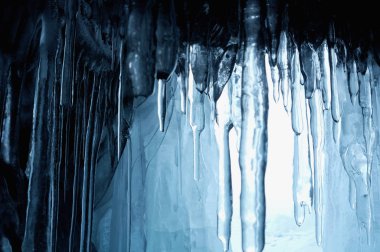 buz mağarasından görünümü. sarkıt gibi dondurulmuş, kristal berraklığında su damlaları tavandan asmak. yükselen güneş lekeli buz. kısmen renkli fotoğraf. merkezi bir nesneye odaklanın. Ekstra sığ alan derinliği.
