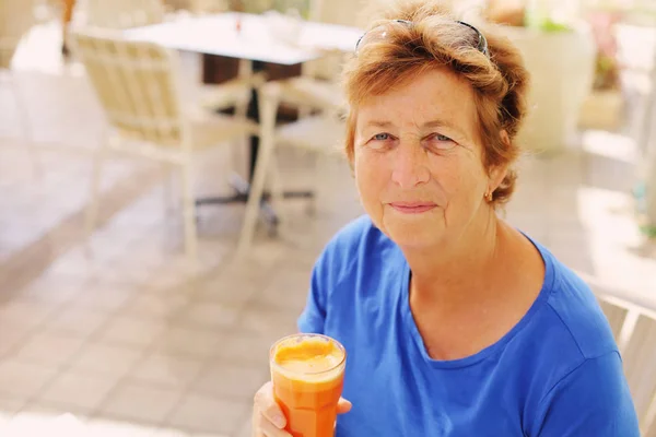 ジュースを飲んだり屋外カフェに座っている年配の女性の肖像画 — ストック写真