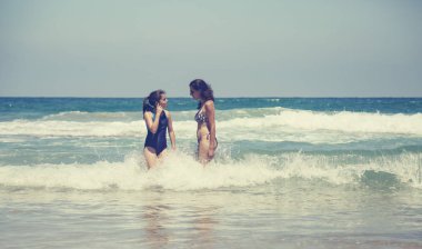 Anne ve kızı eğleniyor birlikte sahilde günbatımında zaman geçirmek için