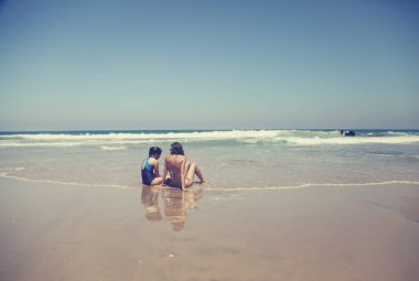 Anne ve kızı eğleniyor birlikte sahilde günbatımında zaman geçirmek için