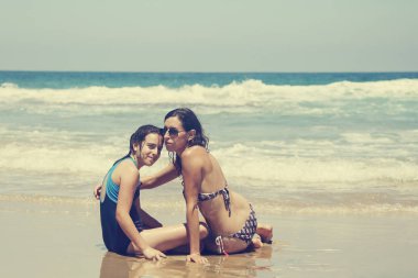 Anne ve kızı eğleniyor birlikte sahilde günbatımında zaman geçirmek için