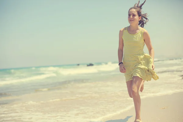 12岁女孩少女少女穿着黄色礼服走在海边 — 图库照片