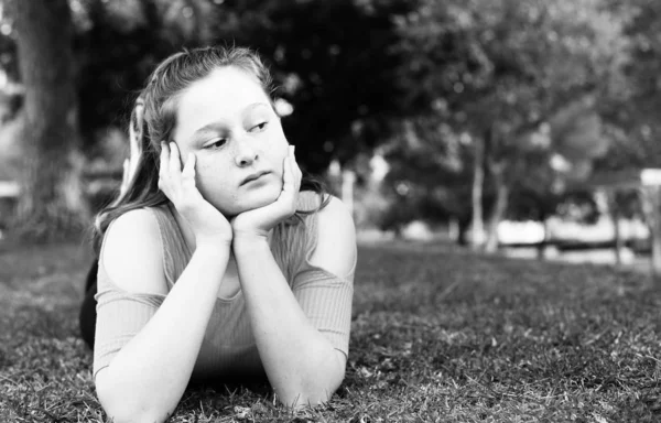 美丽的少女躺在绿色草地上在城市公园 — 图库照片