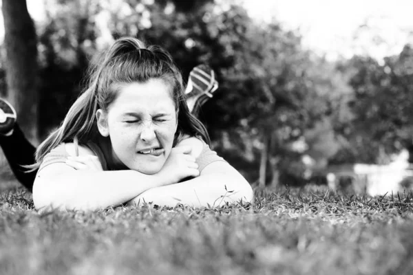 都市公園における緑の草原の上に横たわる美しい十代の少女 — ストック写真