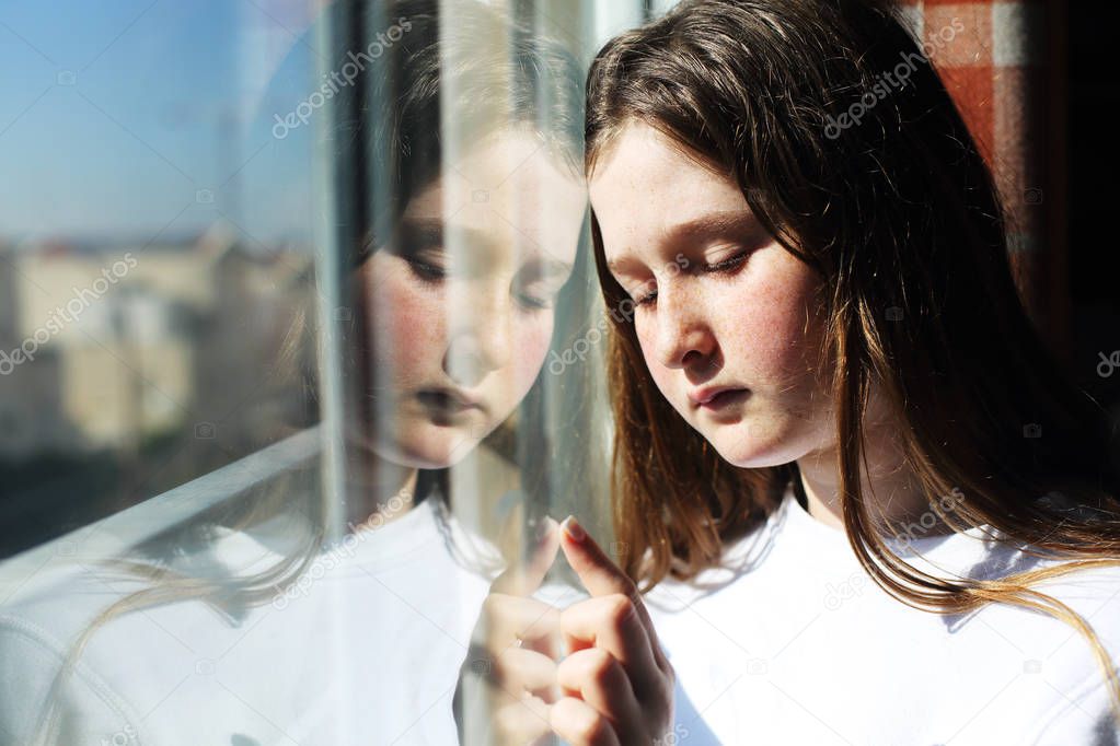 attractive sad teenage girl looking out of the window 