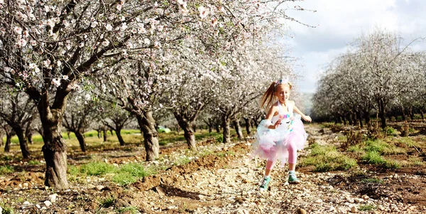 Girl in a unicorn costume jumps outdoors. Spring is around, appl — Stock Photo, Image