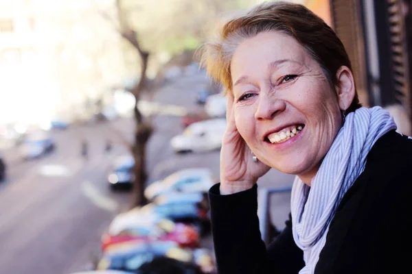 Mooie rijpe vrouw staande op het balkon uitkijken op de st — Stockfoto