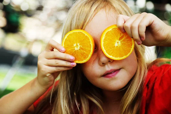 快乐的8岁小女孩笑着拿着橙子片 — 图库照片