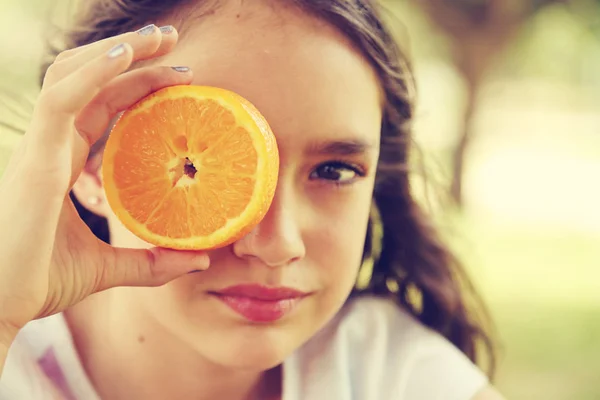 快乐的12岁小女孩笑着拿着橙子片 — 图库照片