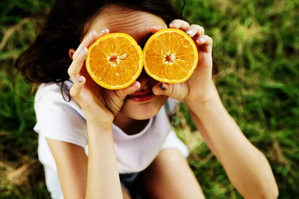 快乐的12岁小女孩笑着拿着橙子片 — 图库照片