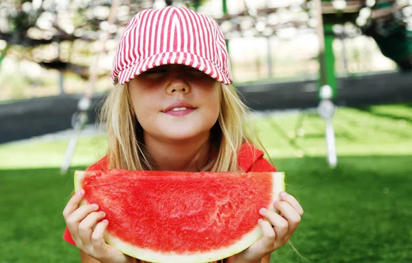 Portret uroczej 8-letniej dziewczynki jedzącej arbuza na th — Zdjęcie stockowe