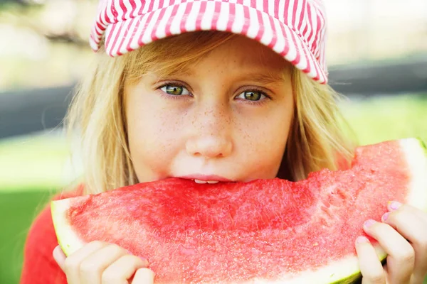 Portret uroczej 8-letniej dziewczynki jedzącej arbuza na th — Zdjęcie stockowe