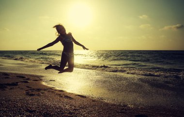 Mutlu küçük kız gün batımında sahilde koşuyor - tatil tatili