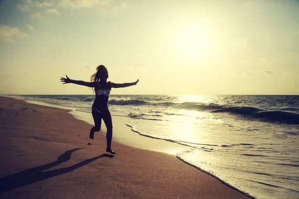 Mutlu küçük kız gün batımında sahilde koşuyor - tatil tatili — Stok fotoğraf