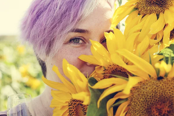 Beauty mature woman with sunflower enjoying freedom on summer sunflower field