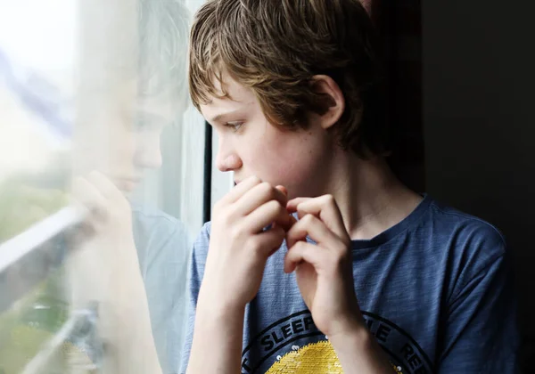 可爱的12岁自闭症男孩看着窗外 — 图库照片