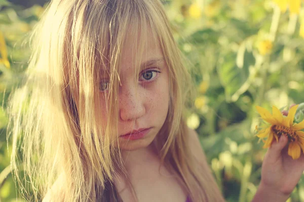 Ayçiçeği tarlasında sevimli üzgün bir kızın portresi.