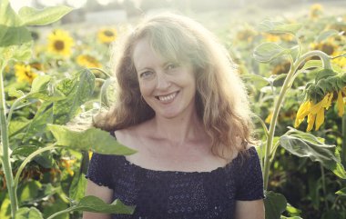 Mutlu olgun bir kadının portresi Ayçiçeği tarlasında özgürlüğün tadını çıkarıyor