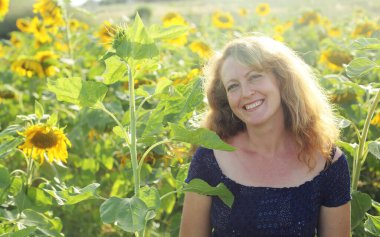 Mutlu olgun bir kadının portresi Ayçiçeği tarlasında özgürlüğün tadını çıkarıyor