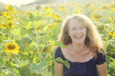 Mutlu olgun bir kadının portresi Ayçiçeği tarlasında özgürlüğün tadını çıkarıyor