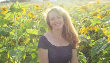 Mutlu olgun bir kadının portresi Ayçiçeği tarlasında özgürlüğün tadını çıkarıyor