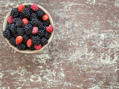 Rustik ahşap bir masa üzerinde bir kapta hasat taze olgun çilek