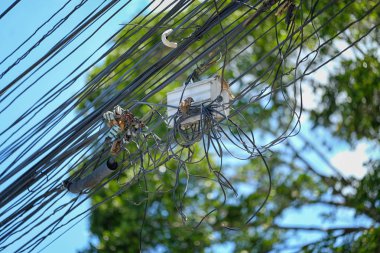 İki yakından elektrik direkleri optik fiber kuşlar ve teller, ipleri askıya alınmış düzensiz yerel Tayland çok sayıda kablo dağınıklığı telefon