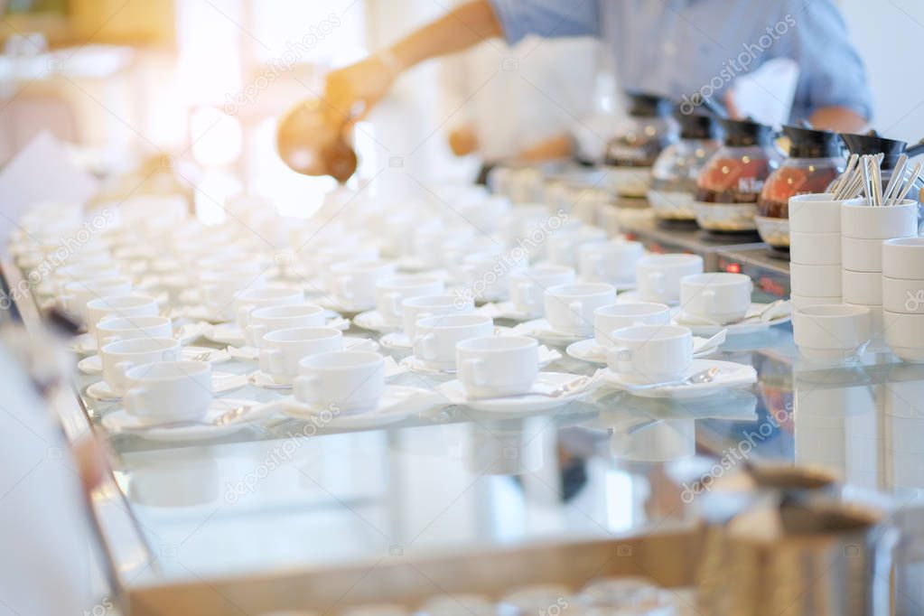 Group of empty Many rows of white ceramic coffee or tea cups and spoons on glass table, in break seminar event.